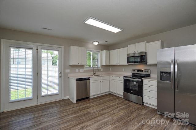 kitchen with stainless steel appliances, a sink, dark wood-style flooring, and light countertops