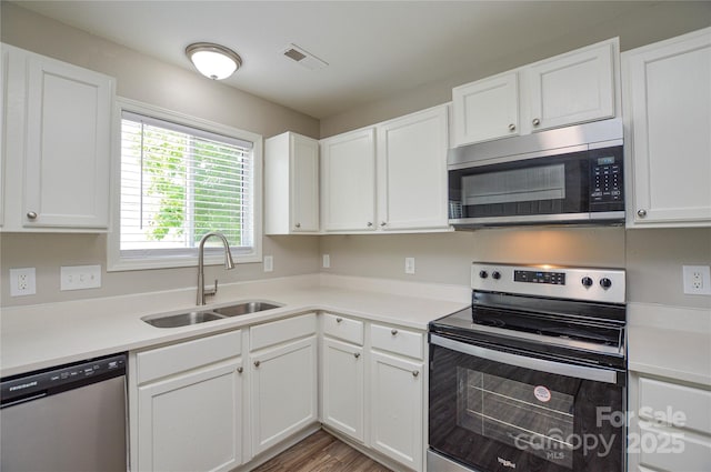 kitchen with stainless steel appliances, a sink, white cabinets, and light countertops