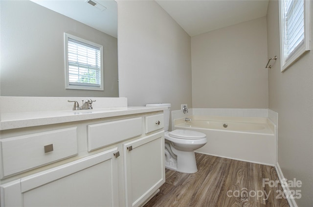 bathroom with wood finished floors, vanity, toilet, and a garden tub