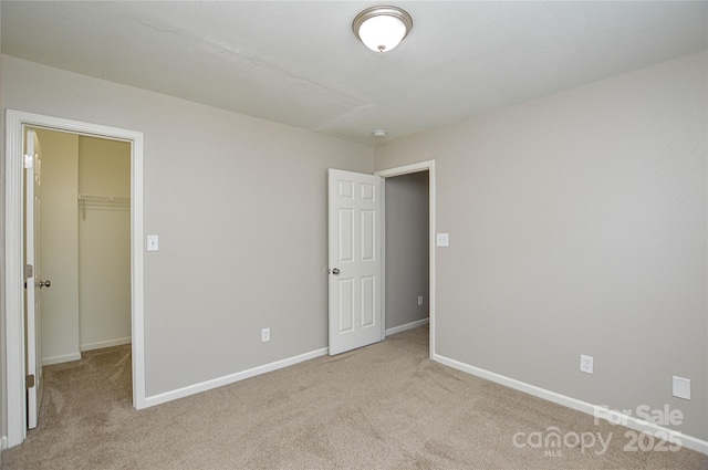 unfurnished bedroom featuring a spacious closet, carpet, baseboards, and a closet