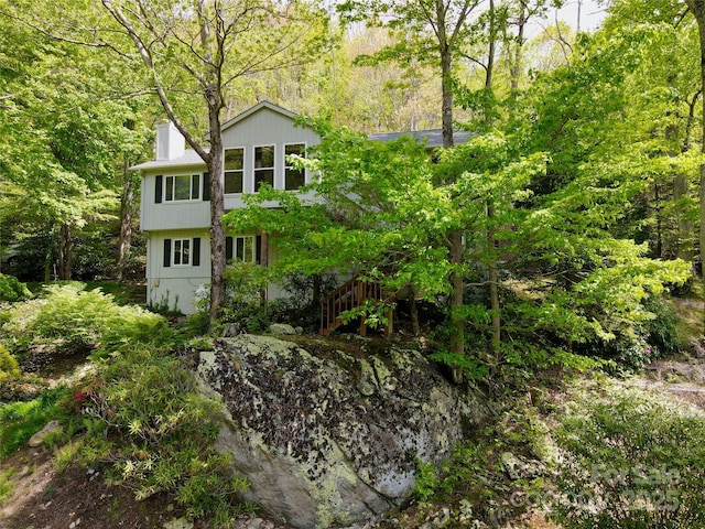 220 Woodwinds Ln, Seven Devils, NC 28604 - rear view of house featuring a chimney, stairs, and a wooded view