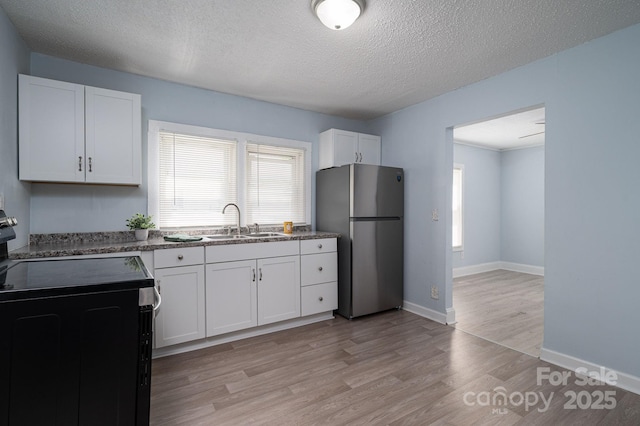 520 E Maple Ave, Gastonia, NC 28054 - kitchen with freestanding refrigerator, black range with electric cooktop, white cabinetry, a sink, and light wood finished floors