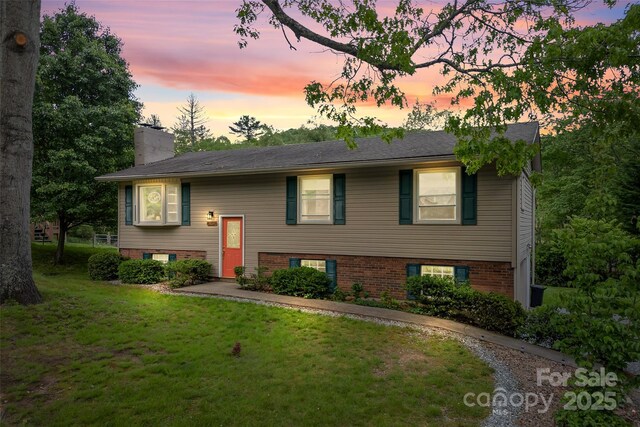 split foyer home featuring a lawn and a chimney