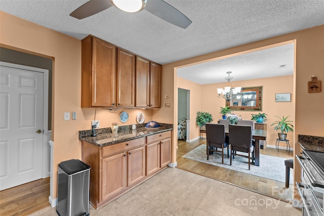 kitchen featuring brown cabinetry, a ceiling fan, a chandelier, double oven range, and a textured ceiling