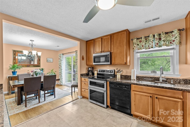 kitchen with stainless steel appliances, a sink, healthy amount of natural light, a textured ceiling, and a chandelier