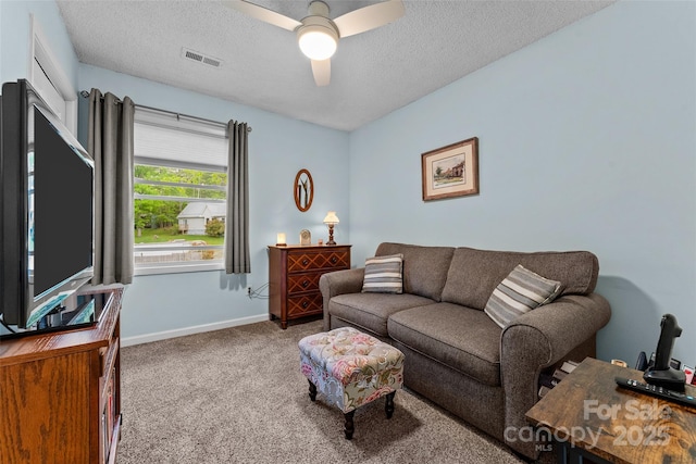 carpeted living room with ceiling fan, a textured ceiling, and baseboards