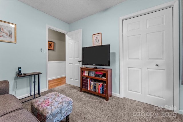 living area featuring carpet flooring, a textured ceiling, and baseboards