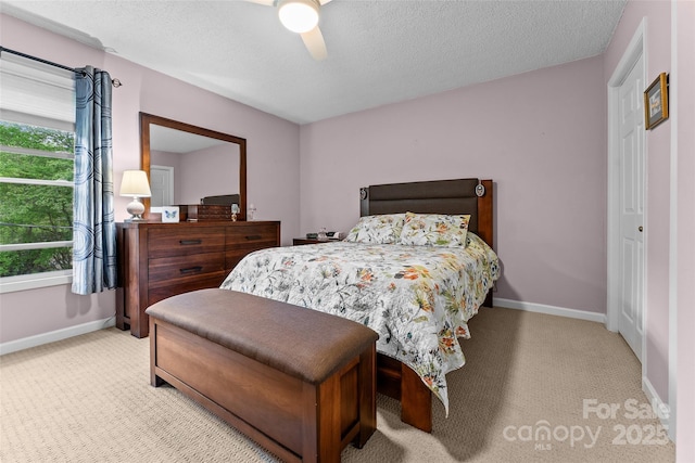 bedroom with light carpet, multiple windows, baseboards, a textured ceiling, and a ceiling fan