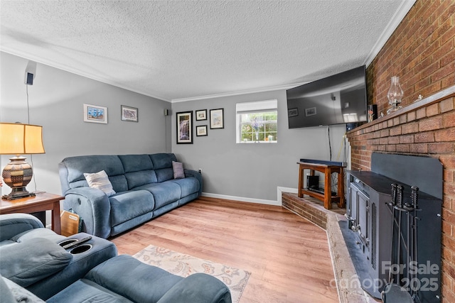 living area with crown molding, light wood-type flooring, a textured ceiling, baseboards, and a brick fireplace