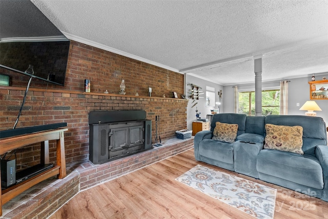living area featuring ornamental molding, a textured ceiling, wood finished floors, and a fireplace