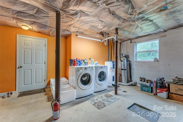 laundry room with washing machine and clothes dryer, water heater, and concrete block wall
