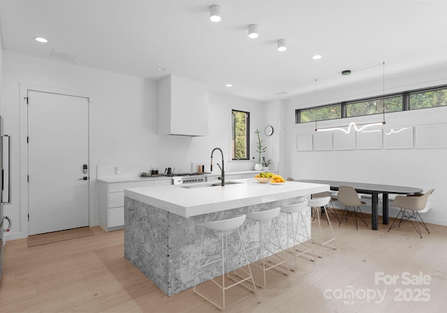 2913 Lake Ave, Charlotte, NC 28208 - kitchen featuring light wood-type flooring, light countertops, plenty of natural light, a center island with sink, and recessed lighting