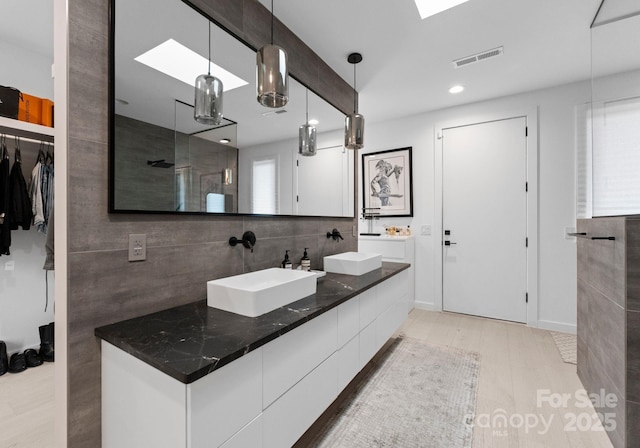 2913 Lake Ave, Charlotte, NC 28208 - full bathroom with double vanity, a walk in shower, a spacious closet, recessed lighting, and backsplash