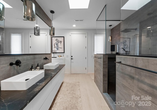 2913 Lake Ave, Charlotte, NC 28208 - bathroom featuring a walk in shower, wood finished floors, double vanity, and recessed lighting