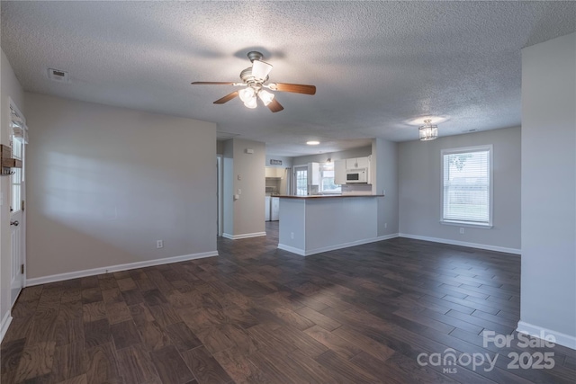 133 Pheasant Run Rd, Troutman, NC 28166 - unfurnished living room with dark wood finished floors, a textured ceiling, ceiling fan, and baseboards