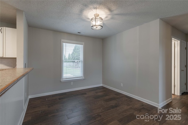 133 Pheasant Run Rd, Troutman, NC 28166 - unfurnished dining area with dark wood-style flooring, a textured ceiling, and baseboards