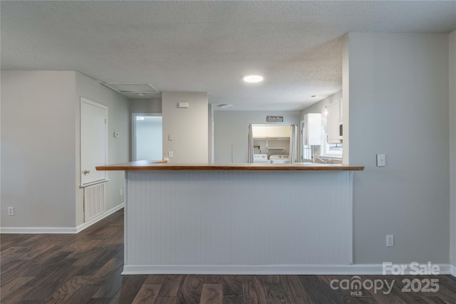 133 Pheasant Run Rd, Troutman, NC 28166 - kitchen featuring dark wood-type flooring, baseboards, a peninsula, and a textured ceiling
