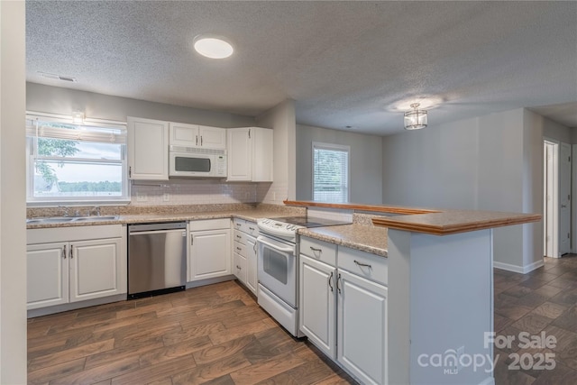 133 Pheasant Run Rd, Troutman, NC 28166 - kitchen featuring white appliances, a sink, a peninsula, white cabinetry, and a textured ceiling