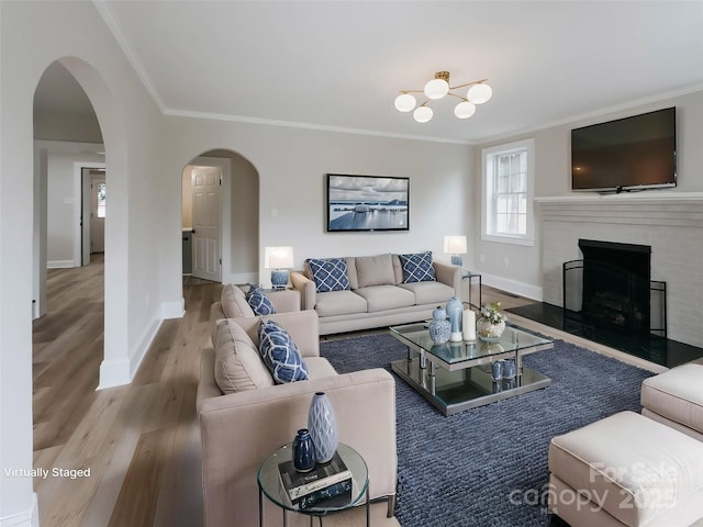 living area with arched walkways, ornamental molding, wood finished floors, a fireplace, and baseboards