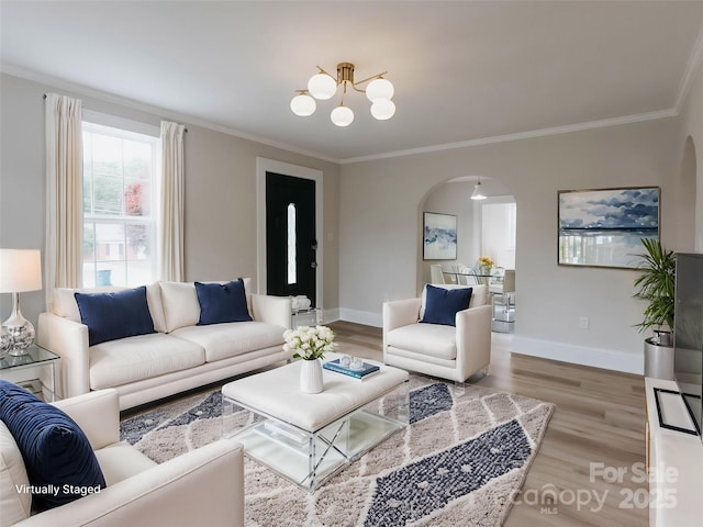 living room with arched walkways, a chandelier, crown molding, wood finished floors, and baseboards
