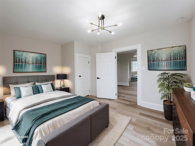 bedroom with baseboards, a chandelier, and light wood-style floors