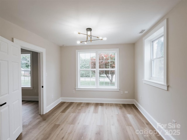 unfurnished dining area with a chandelier, plenty of natural light, light wood-style floors, and baseboards