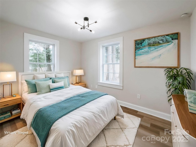 bedroom with wood finished floors, baseboards, and a chandelier