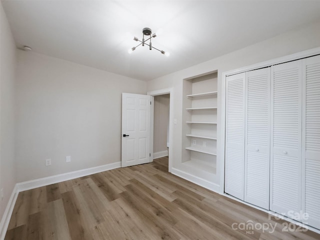 unfurnished bedroom with wood finished floors, baseboards, and a closet