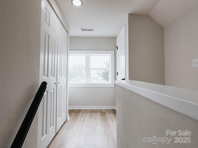 hall with light wood-style floors, an upstairs landing, recessed lighting, and baseboards