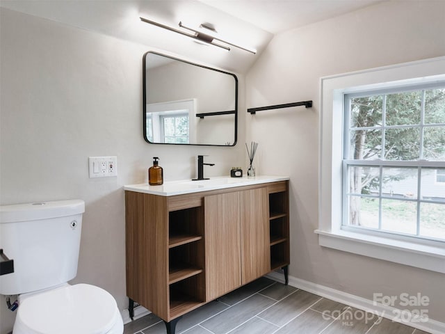 bathroom with toilet, vanity, and baseboards