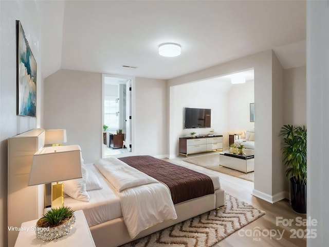 bedroom with wood finished floors and vaulted ceiling