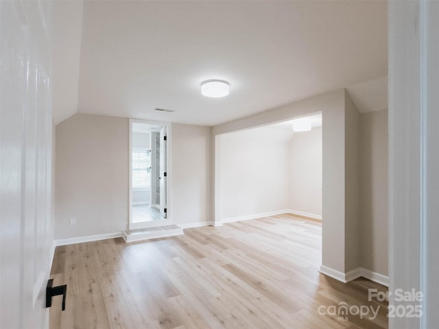 spare room with wood finished floors, baseboards, and vaulted ceiling