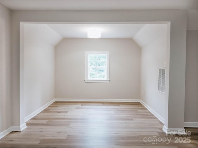 bonus room with light wood-style floors, lofted ceiling, and baseboards