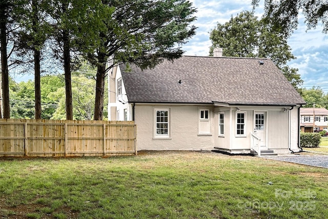 rear view of house featuring roof with shingles, a chimney, entry steps, and stucco siding