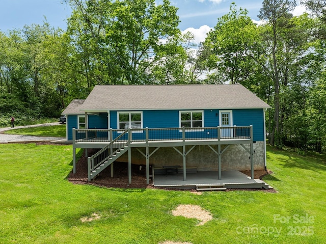 rear view of property featuring a deck, a yard, stairway, a patio, and a shingled roof