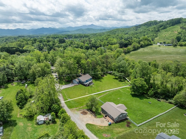 aerial view of property and surrounding area with a heavily wooded area, mountains, and property boundaries highlighted