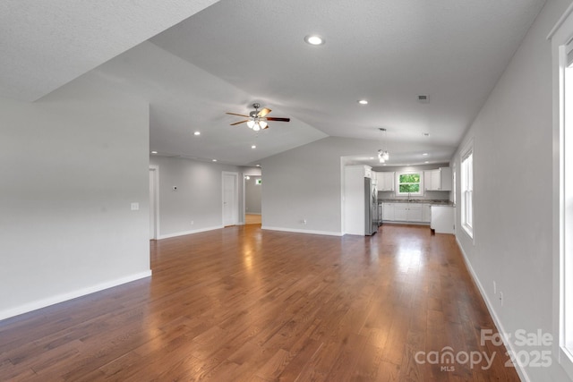 unfurnished living room featuring ceiling fan, lofted ceiling, dark wood-type flooring, baseboards, and recessed lighting