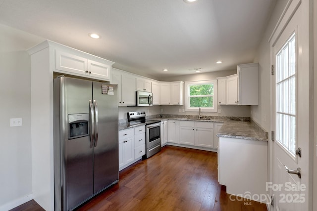 kitchen featuring stainless steel appliances, a sink, dark wood finished floors, white cabinets, and recessed lighting