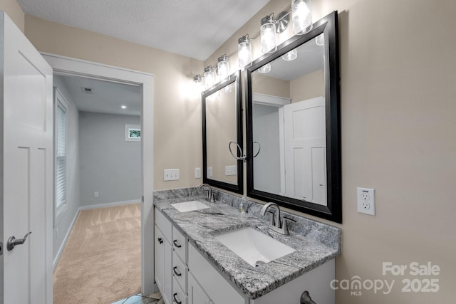 full bath with baseboards, double vanity, and a textured ceiling