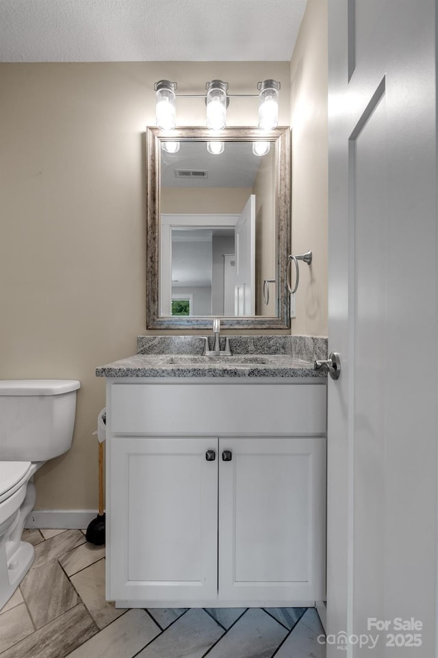 bathroom with toilet, vanity, and baseboards