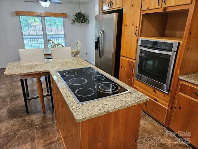 3191 Piedmont Rd, Morganton, NC 28655 - kitchen with stainless steel appliances, a kitchen island, brown cabinets, and ceiling fan