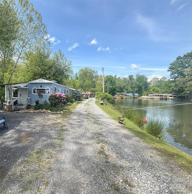 view of road with a water view, entry steps, and view of scattered trees