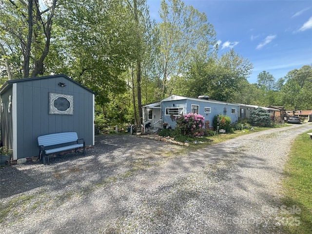 view of front of house featuring an outdoor structure, a storage shed, and view of wooded area