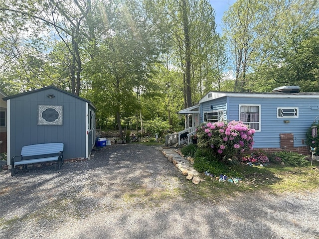 view of side of property featuring an outbuilding, view of wooded area, and a storage unit