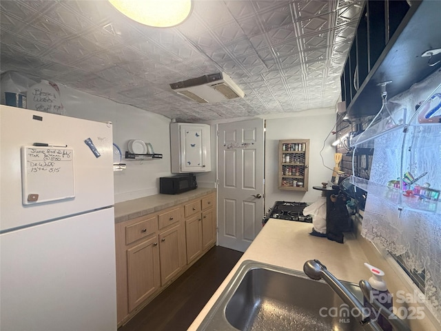 kitchen with freestanding refrigerator, an ornate ceiling, black microwave, light countertops, and a sink