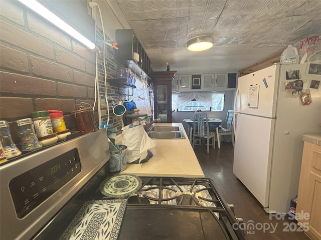 kitchen with freestanding refrigerator, an ornate ceiling, a sink, dark wood-style floors, and gas stove