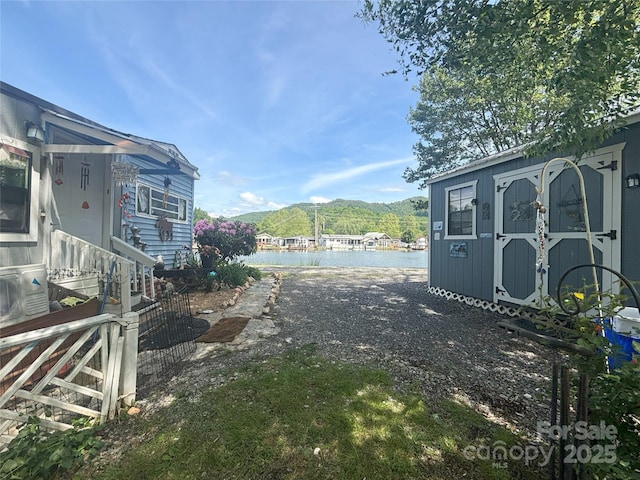 view of yard with a storage shed, a water and mountain view, and an outbuilding
