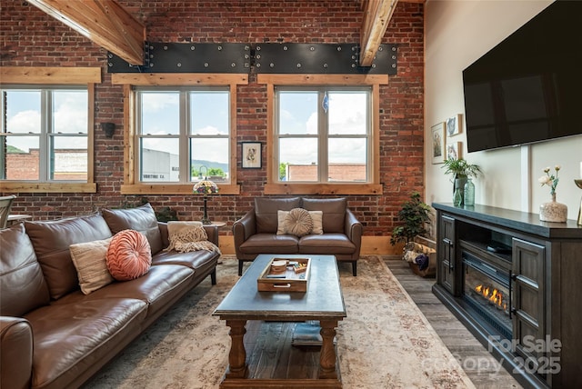 14 N Main St Unit 2, Waynesville, NC 28786 - living room with brick wall, light wood-type flooring, a glass covered fireplace, a high ceiling, and beam ceiling
