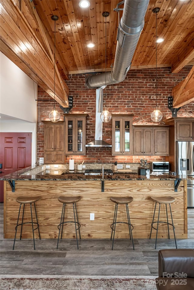 14 N Main St Unit 2, Waynesville, NC 28786 - kitchen featuring appliances with stainless steel finishes, a breakfast bar area, wall chimney range hood, brick wall, and brown cabinets