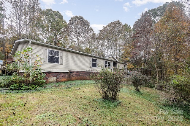 view of side of property featuring a lawn, a wooden deck, and crawl space